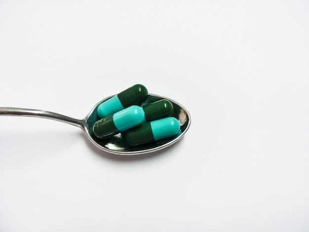 medicine pills, tablets and capsules in spoon on white background 