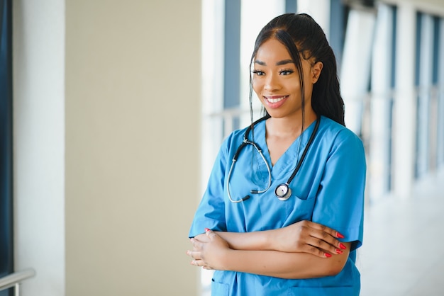 写真 医学、職業、ヘルスケアの概念-病院の背景に聴診器を持つ幸せな笑顔のアフリカ系アメリカ人女性医師