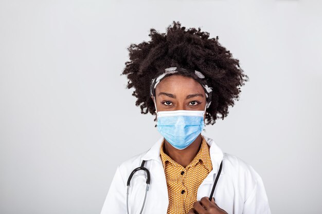 アフリカ系アメリカ人の女性医師や科学者が灰色の背景の上に保護面膜をかぶっている医学の職業と医療コンセプトのクローズアップ