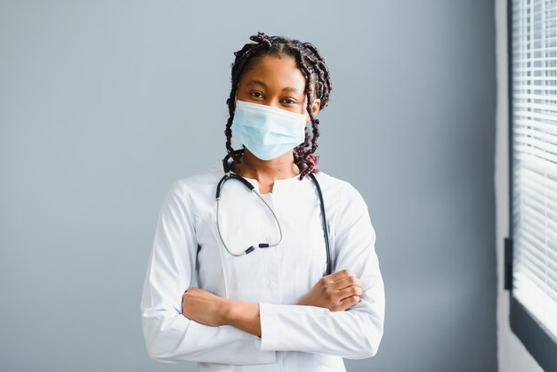 医療専門家とヘルスケアの概念は、保護フェイシャルマスクでアフリカの女性医師または科学者のクローズアップ