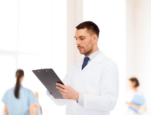 medicine, profession, and healthcare concept - serious male doctor with clipboard writing prescription over white background