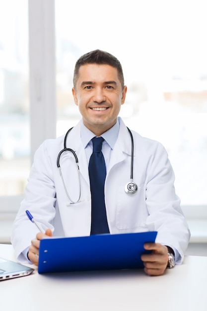 Foto concetto di medicina, professione, tecnologia e persone - medico maschio felice con appunti in studio medico