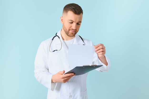 Medicine profession technology and people concept happy male doctor with clipboard and stethoscope over blue background