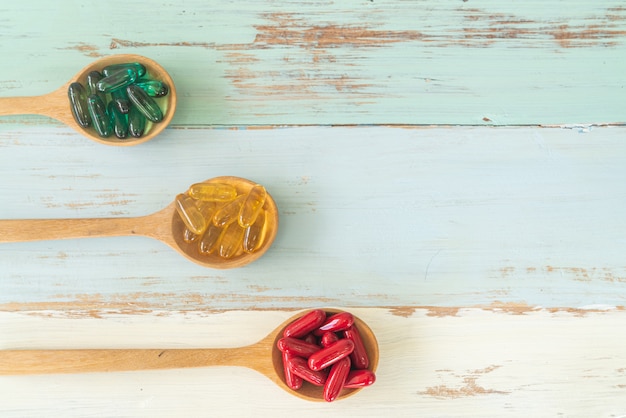 Medicine on spoons on wooden table, top view