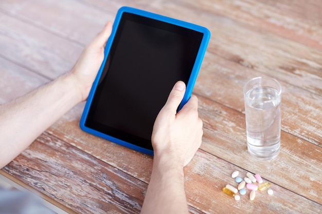 의학, 기술, 영양 보조제, 그리고 사람들의 개념 - 태블릿 PC 컴퓨터, 알약, 물을 탁자 위에 얹은 남성의 손 클로즈업
