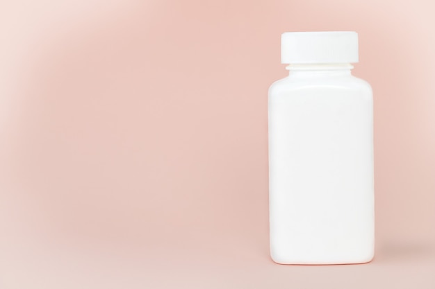 Bottiglia di medicina bianca su sfondo rosa