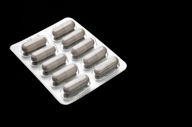 Medicine White capsule pills in blister packs on a black background Healthcare concept