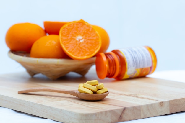 Medicine in wooden spoon on blurred orange slice and bottle capsule background,