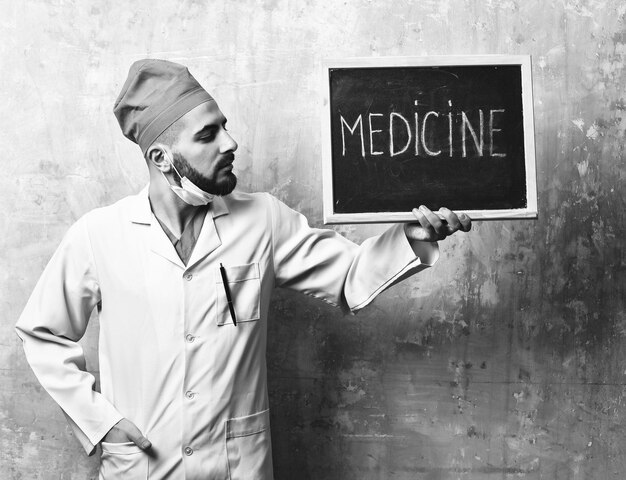 Medicine word written on blackboard which is held by doctor