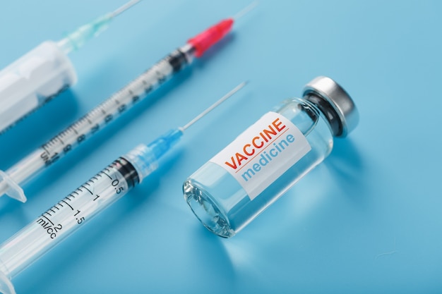 Medicines with syringe Vaccine ampoule on a blue