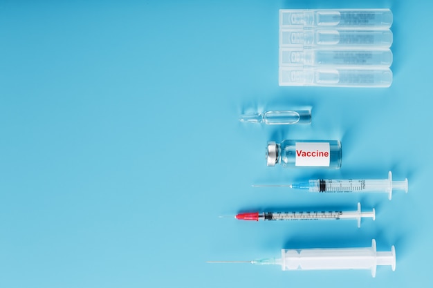 Фото Лекарства со шприцем в ампуле вакцины на синем