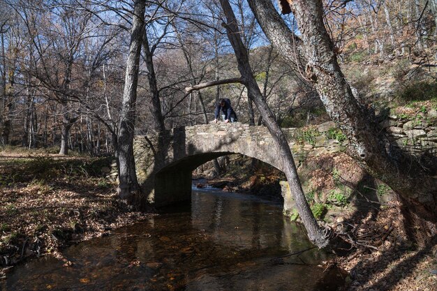 Photo medieval bridge with hiker on the pelagallinas river in the northern mountains of guadalajara spain