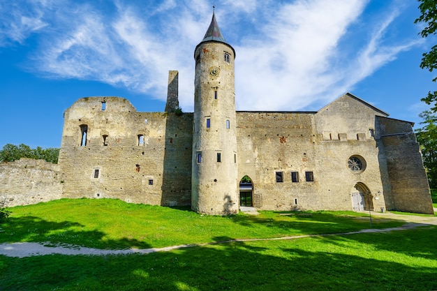 Medieval castle with high tower with clock and white clouds in sunny day. Haapsalu Estonia.