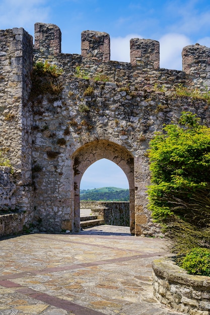 Medieval castle with stone wall and arched entrance gate in sunny day