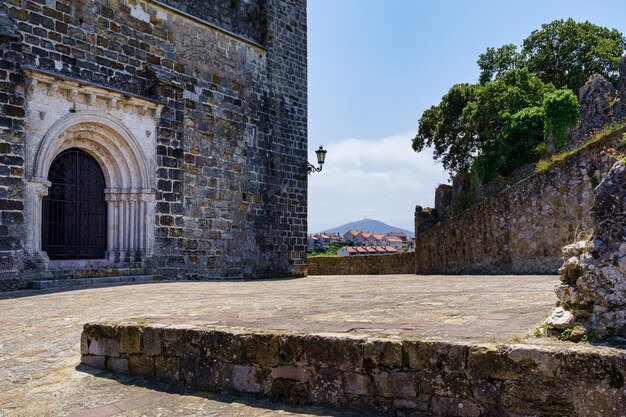 Medieval church with arched entrance door and houses in the distance