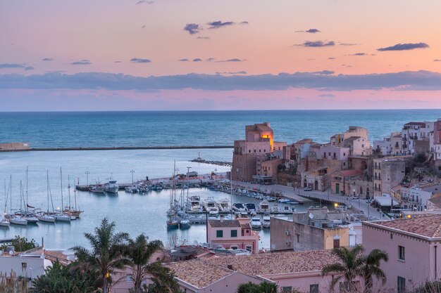 Medieval fortress in Cala Marina, harbor in coastal city Castellammare del Golfo at pink sunrise, Sicily, Italy