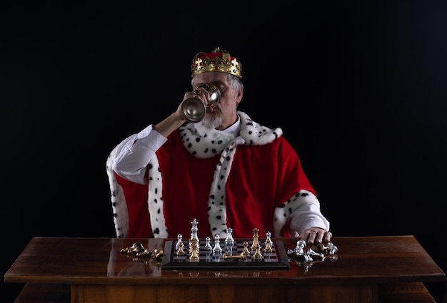 medieval king playing chess, black studio background