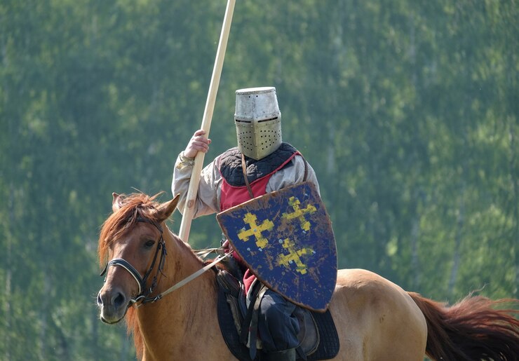 Medieval knight with a spear riding a horse on a background of green forest in the field. historical reconstruction