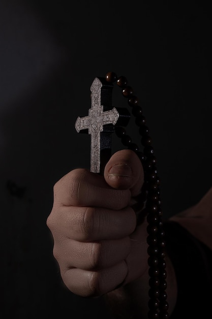 Medieval monk praying with closed eyes with wooden cross in\
arms close up