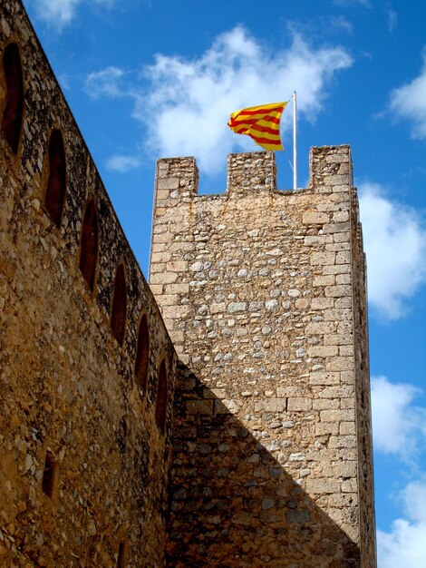 Foto castello di pietra medievale con bandiera della catalogna contro il cielo