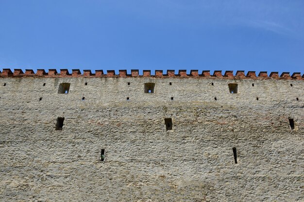 들쭉날쭉한 벽돌 꼭대기가 있는 성이나 요새의 중세 돌담. 푸른 하늘 위