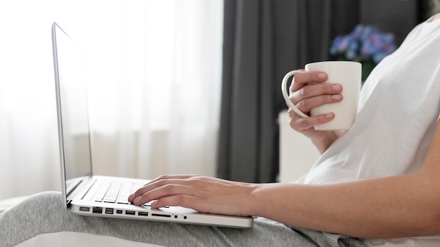 Medio geschotene vrouw die van huis het drinken koffie werkt