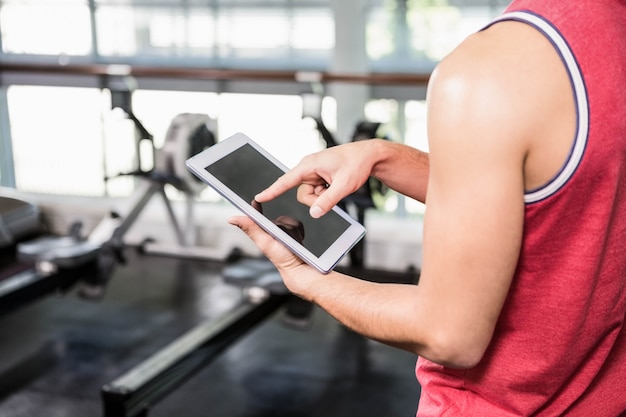 Medio sectie van de mens die tablet in de gymnastiek gebruikt