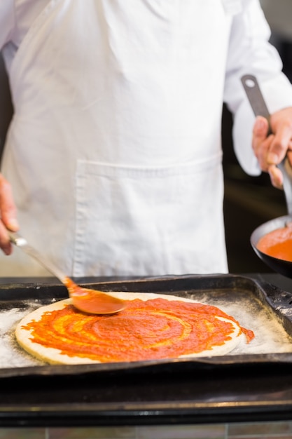Medio sectie van een chef-kok die pizza in keuken voorbereidt
