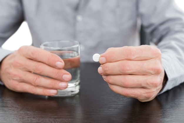 Medio sectie van een glas van de mensenholding water en pil