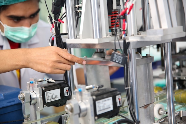 Medio volwassen mannelijke ingenieur die machineonderdeel onderzoekt op een productielijn in een fabriek.