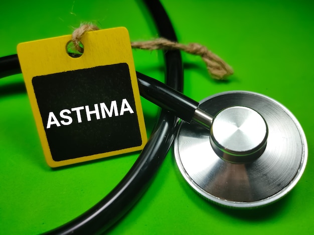 Medisch concept met tekst ASTMA op houten bord met stethoscoop op groene achtergrond