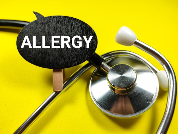 Medisch conceptWord ALLERGIE op houten bord met stethoscoop op gele achtergrond