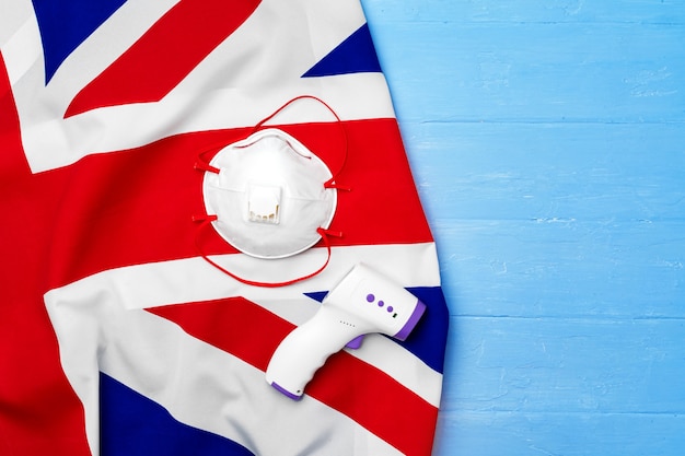 Medisch gezichtsmasker en contactloze thermometer op Britse vlag, coronavirus-concept