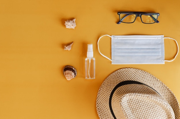 Medisch gezichtsmasker, handschoenen, handdesinfecterend middel, zonnebril en strandhoed. Reizen in pandemie, coronavirus