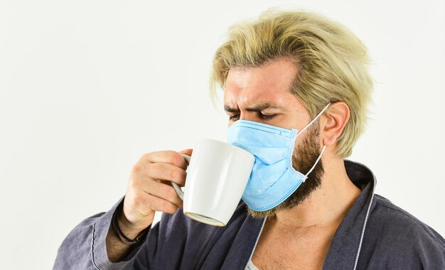 Medisch masker als corona-bescherming man drinkt koffie in ademhalingsmasker beschermend masker coronavirus pandemie-uitbraak dokter ademhalingsmasker ziekenhuis of vervuiling beschermen gezichtsmaskering