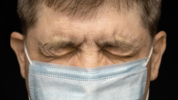 Medisch masker op het gezicht van een man met gesloten ogen Bescherming tijdens een pandemie