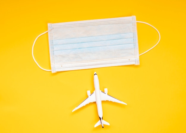 Medisch masker, reizen, vliegtuigen, gele achtergrond, problemen met reizen door covid-19