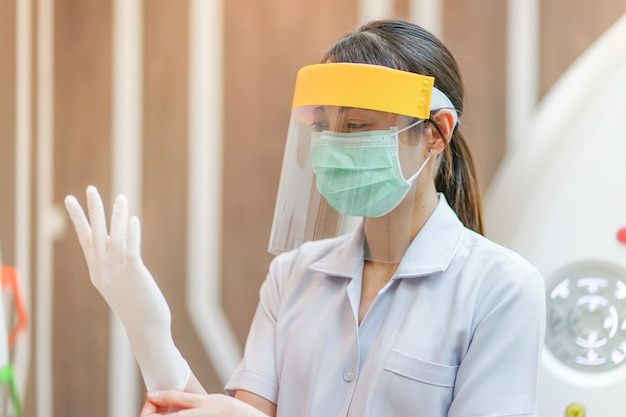 Foto medisch personeel draagt een gelaatsscherm, een medisch masker en een medisch bosje ter bescherming van het coronavirus covid-19 virus in het ziekenhuis