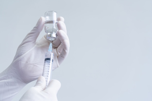 Medisch personeel in PBM's houdt spuiten en vaccins vast voor de behandeling van het COVID-19-virus. Medische onderzoekers in het lab testen vaccins voor de behandeling van virale ziekten.