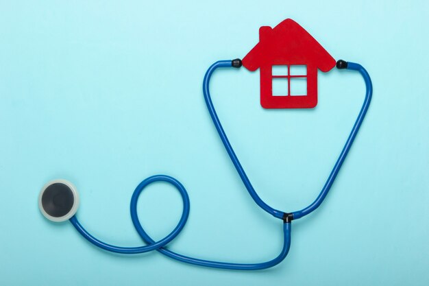 Medisch stilleven. Stethoscoop, beeldje van het ziekenhuis huis op blauwe achtergrond. Plat leggen