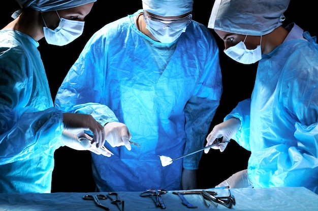 Medisch team dat operatie uitvoert Groep chirurg aan het werk in de operatiekamer, blauw getint