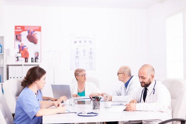 Medisch team interactie tijdens een vergadering in vergaderruimte tijdens discussie over gezondheid. Kliniekdeskundige therapeut in gesprek met collega's over ziekte, medisch professional