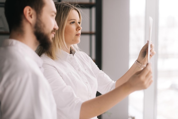 Medisch team van twee jonge artsen bespreken röntgenfoto van patiënt in vergaderruimte