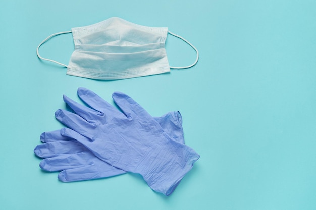 Medisch wegwerpmasker en handschoenen op een turquoise achtergrond