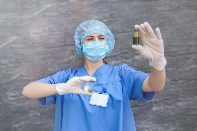 Medisch werker in blauw uniform met ampullen met vaccins van verschillende kleuren op abstracte achtergrond