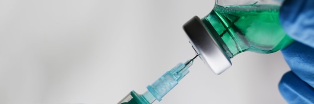 Medisch werker verzamelt vloeistof uit glazen fles in spuit