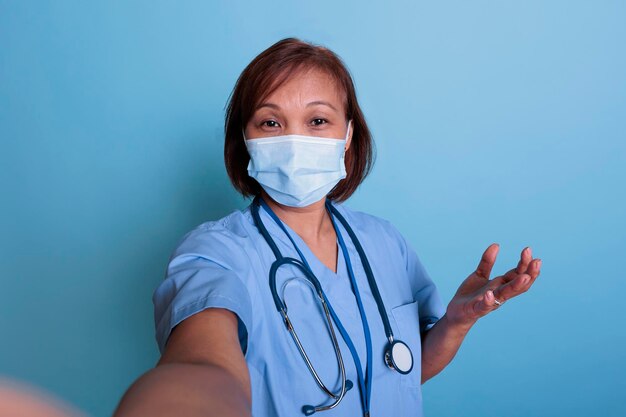 Medische assistent draagt een beschermend gezichtsmasker om infectie met covid19 te voorkomen tijdens een online videogesprek in gesprek met een arts op afstand. Artsverpleegkundige die gezondheidszorgbehandeling bespreekt