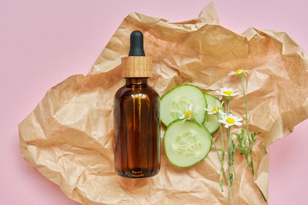 Medische biologische kruidencosmetica natuurlijke ingrediënten kamille bloemen komkommer ambachtelijk papier roze achtergrond bovenaanzicht