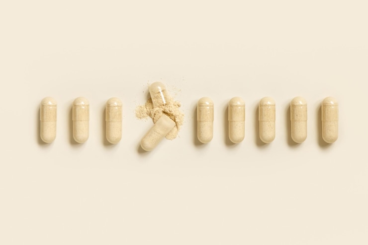 Foto medische capsules in een rij met een geopend om beige poeder te tonen op licht beige top view preventieve geneeskunde en gezondheidszorg voedingssupplementen en vitaminen