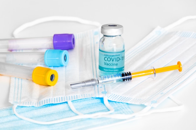 Medische fles, flesjes, spuiten en gezichtsmasker. coronavirusvaccin - nieuw vaccin tegen coronavirus sars-cov-2 op laboratoriumtafel. vaccinatiesessie en verbetering van de immuniteit.